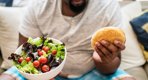 Person eating a salad and a burger.